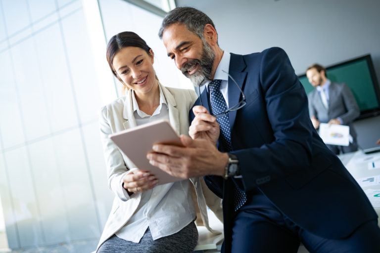 Happy business colleagues in modern office using tablet